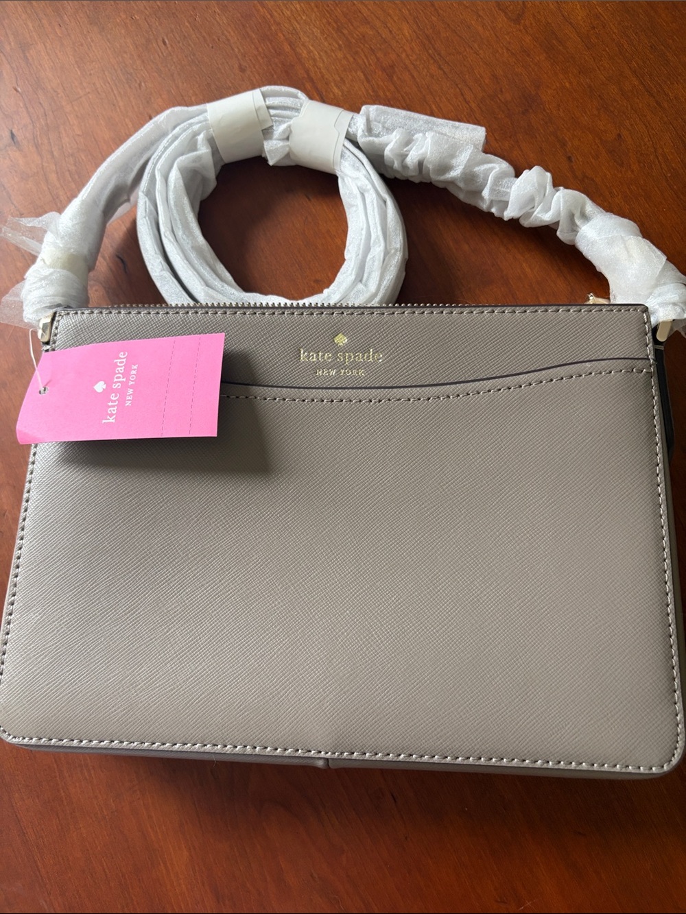 kate spade taupe crossbody with gold logo and pink tag